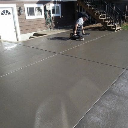 Technician applying sealer to a coloured concrete slab