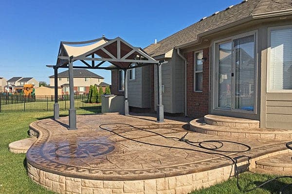 Stamped concrete patio under a pergola after semi-gloss sealing