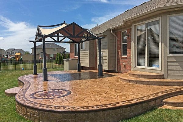 Stamped concrete patio under a pergola before sealing