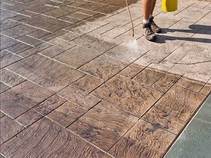 TriCity technician pressure washing a stamped concrete patio before sealing