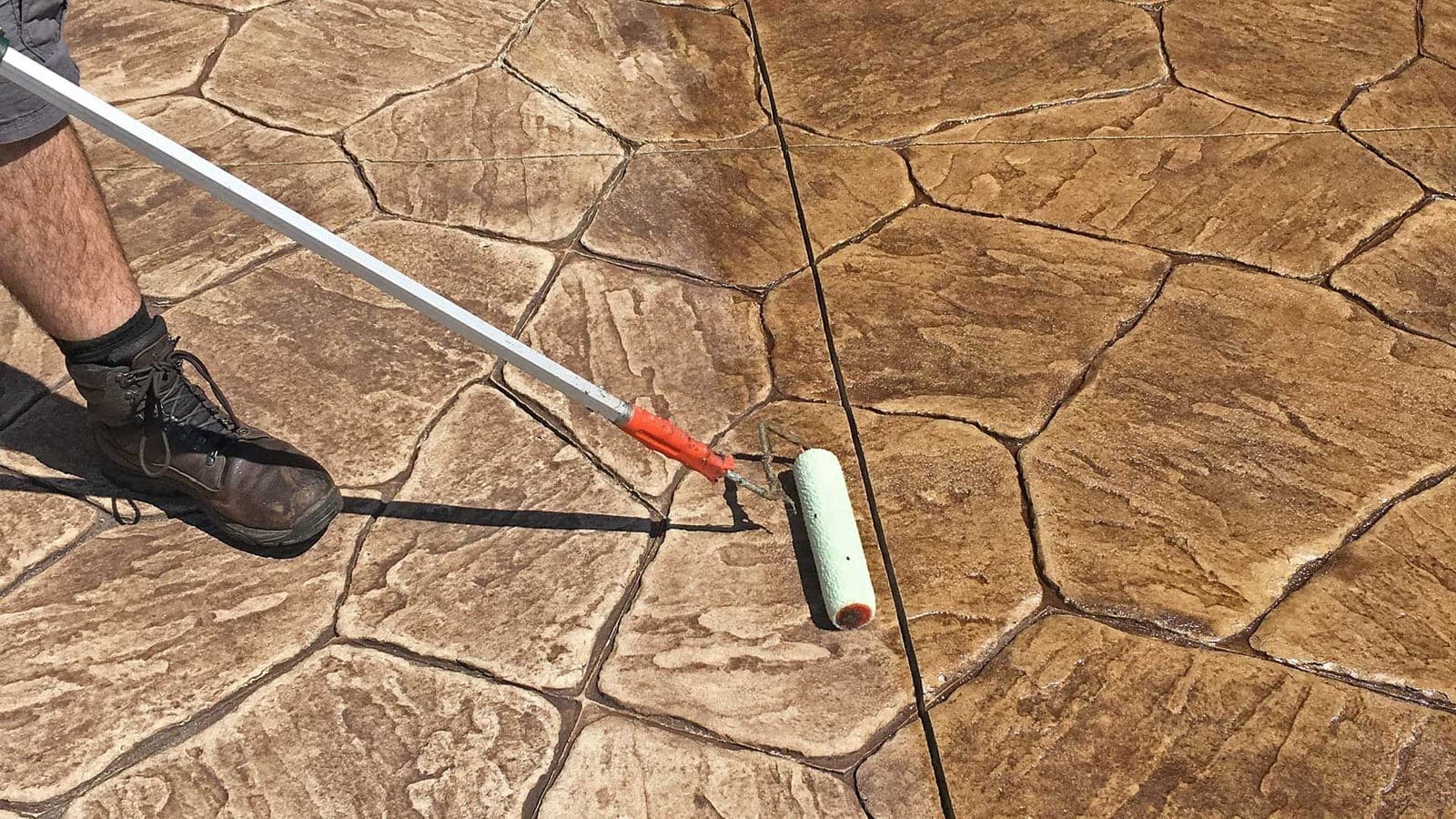 Technician assessing an old sealer coating on a concrete driveway in Oxford County before resealing