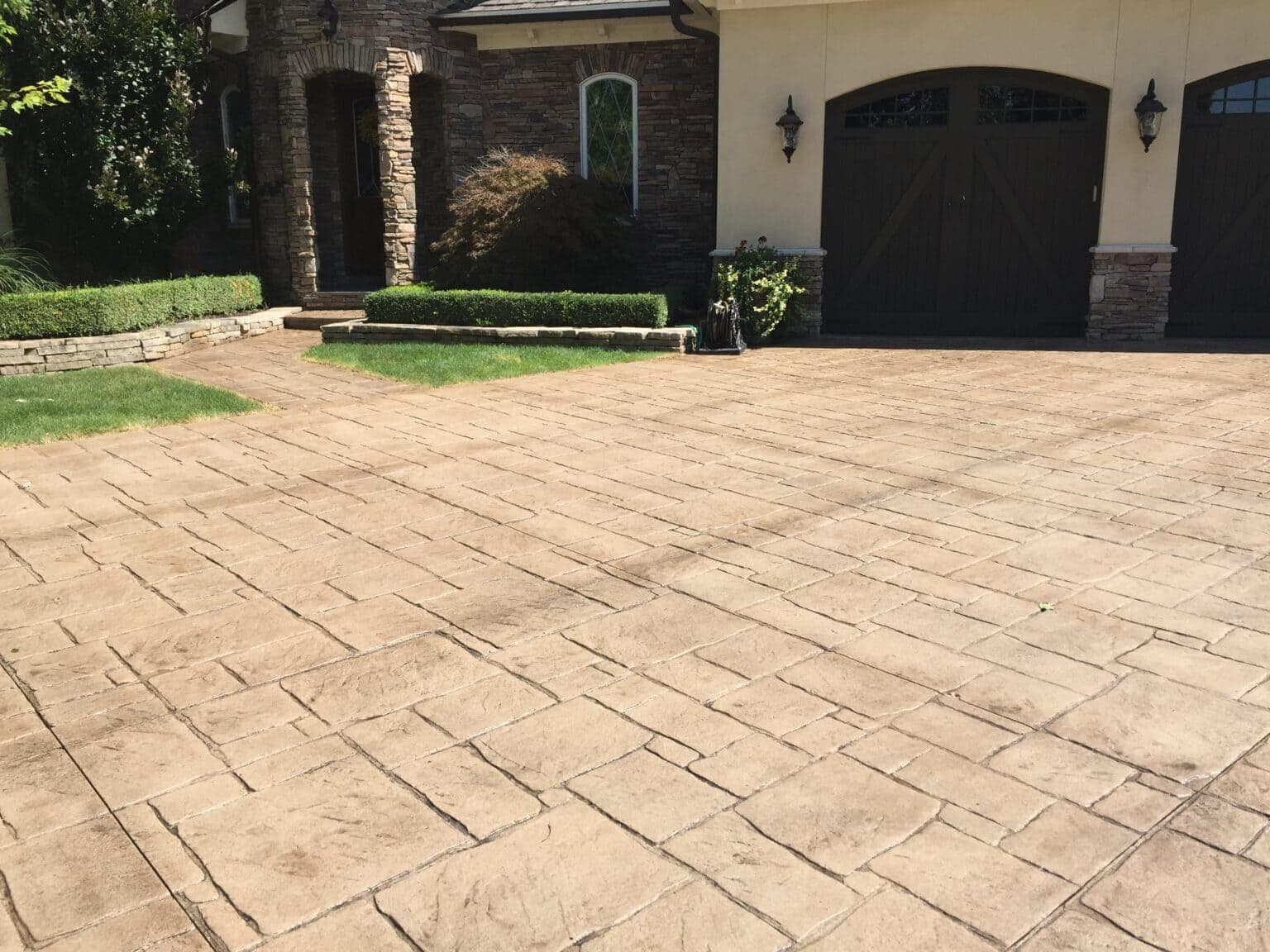 Sealed stamped concrete driveway in front of a stone garage in Southwestern Ontario